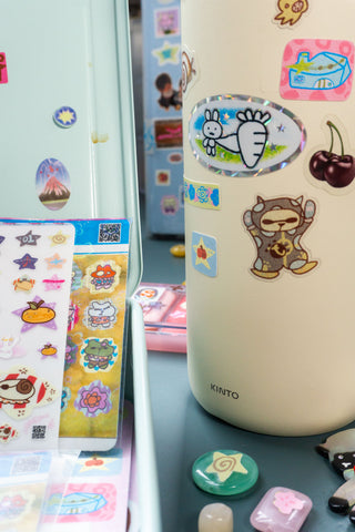 Kinto water bottle with colorful stickers on a blue surface
