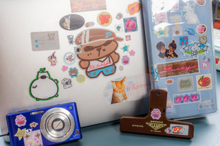 Close up of laptop with stickers and a propped up planner