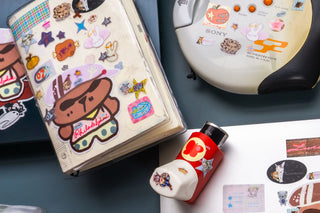 Sticker-covered notebook, inhaler, and other items on a blue surface