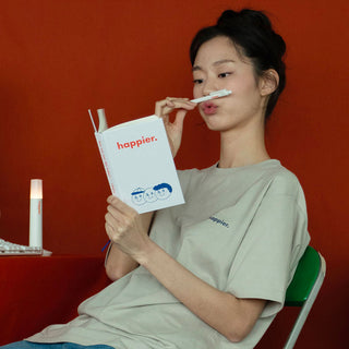 Person holding a book titled 'happier' with a red background