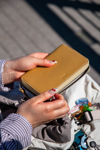 Person holding a tan wallet with a blurred background