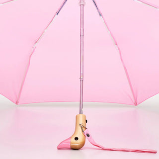 Pink umbrella with a wooden duck  handle on a light pink background