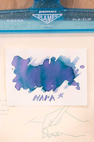 Ink swatch card with blue-purple splash and 'HAMA *+' text