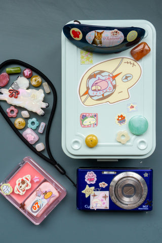 Small camera, sheep clip, toolbox, and colorful beads decorated with stickers on a blue background