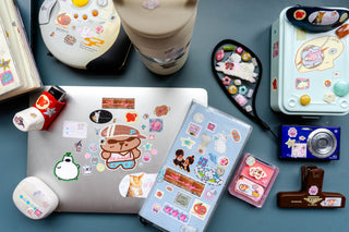 Collection of stationery items with stickers on a blue surface