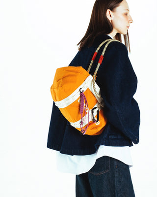 Person wearing an orange bag with straps and keychains on a white background