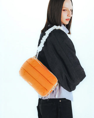 Person wearing an orange bag and white straps on a white background