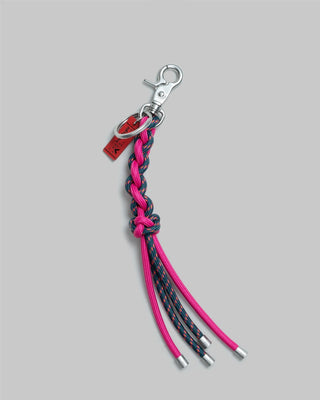 Braided keychain with pink and blue straps on a beige background