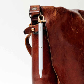 Brown leather bag with a white ystudio pen attached on a white background